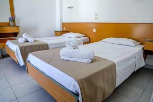 two beds in a hotel room with towels on them at Barvas studios Lindos in Líndos +3 photos