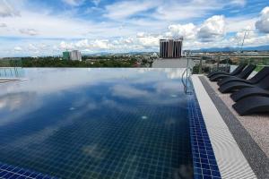 a swimming pool with lounge chairs on top of a building at Kozi Square New SGH Cozy Home LV5B in Kuching