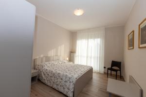 1 dormitorio con 1 cama, 1 silla y 1 ventana en Rossini15 - garage privato, en Alba