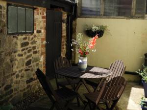 a table with chairs and a vase with flowers on it at Sycamores Barn - Detached, Private, Secluded Country Retreat in Brighstone