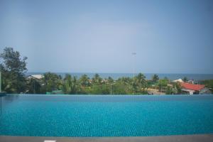 a blue swimming pool with trees in the background at Altrude By The Sea in Candolim