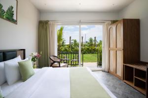 a bedroom with a large white bed and a balcony at Sibaya Beach Resort, Morjim in Morjim