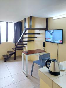 a room with a table and a tv and a staircase at airobedz MANILA - near Taft Avenue in Manila