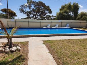 a swimming pool with two lounge chairs next to it at East West Motel Ceduna in Ceduna
