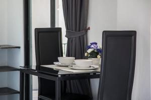 a black table with two cups and a vase of flowers at West Key Kamala Apartment in Kamala Beach