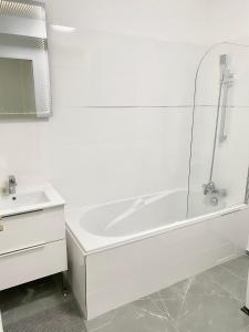 La salle de bains blanche est pourvue d'une baignoire et d'un lavabo. dans l'établissement Modern Apartment Disneyland Paris, à Chessy