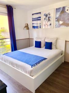 uma cama branca com almofadas azuis num quarto em Modern Apartment Disneyland Paris em Chessy