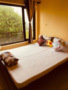 łóżko z poduszkami w pokoju z oknem w obiekcie Aashiyana Homestay w mieście Bhimtal