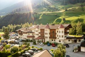 ein großes Gebäude mit vielen Autos auf einem Parkplatz in der Unterkunft Appartements Alpenschlössl in Neustift im Stubaital