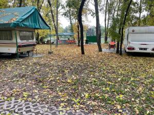 a rv and a tent in a park with leaves at Tisza-beach wild camping 5 in Szeged