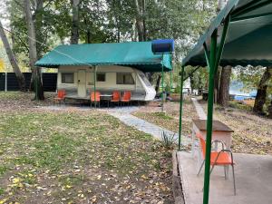 una caravana con un dosel azul en un parque en Tisza beach Wild Camping 2, en Szeged
