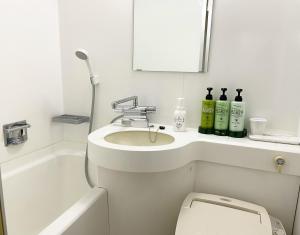 a bathroom with a sink and a toilet and a mirror at Yono Daiichi Hotel in Saitama