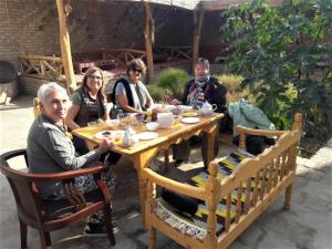 a group of people sitting around a wooden table at madrasah Polvon-Qori boutique hotel in Khiva
