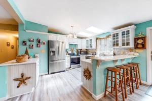 uma cozinha com paredes azuis e armários brancos e bancos de bar em Summer Daze em Edgartown