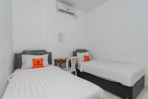 two beds with orange pillows in a room at KoolKost near Alun Alun Kota Bandung 2 - Male Only in Bandung