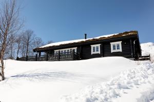 una cabaña de madera con nieve delante en Utsikten en Sykkylven