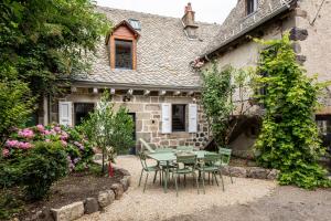 a patio with a table and chairs in front of a house at Chez Mimi - La Petite Maison in Raulhac