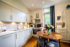 una cocina con armarios blancos y una mesa de madera con flores en Middlethorpe Manor - No 6 Tranquility & Ease en York