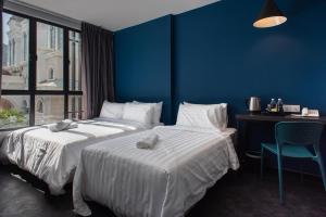 two beds in a room with a blue wall at Chariton Hotel Bagan in Butterworth