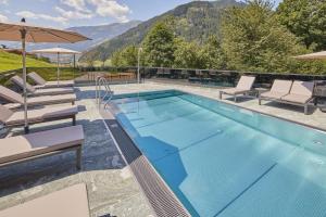 uma piscina com espreguiçadeiras e uma montanha em Hochfeldhof em Zell am Ziller