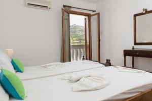 two beds in a room with a mirror and a window at Smaragda Hotel in Marathokampos