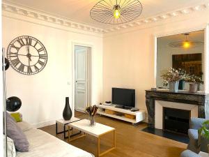 a living room with a fireplace and a clock on the wall at Real Parisian apartment with 2 bedrooms and AC in Paris