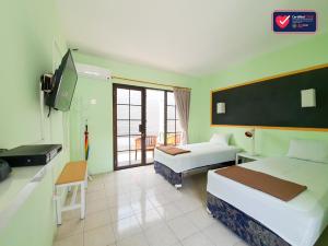 una camera d'albergo con due letti e una TV a schermo piatto di Hotel Griya Wijaya ad Ambarawa