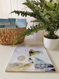 Ein Buch liegt auf einem Tisch neben einer Pflanze. in der Unterkunft Apartment GoKaprun mit Blick auf die Berge in Kaprun