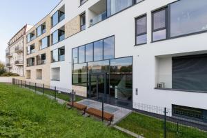 an exterior view of a white building with glass windows at Riva Verona Apartments by Renters Prestige in Krakow