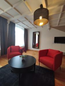ein Wohnzimmer mit 2 roten Stühlen und einem Tisch in der Unterkunft Exclusive Suite South Central in Leipzig