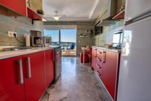 uma cozinha com armários vermelhos e vista para o oceano em Casa de Luz em La Herradura
