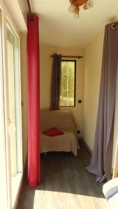 a bedroom with a bed with red curtains and a window at Les Pucines bis Bas de villa 29 m2 luxe rez de jardin climatisation plein sud in Six-Fours-les-Plages