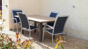 a wooden table and four chairs next to a wall at Les Pucines bis Bas de villa 29 m2 luxe rez de jardin climatisation plein sud in Six-Fours-les-Plages