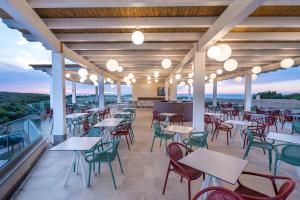 ein Restaurant mit Tischen und Stühlen auf einem Balkon in der Unterkunft Amareclub Red Sun Village in Isola Rossa