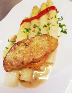 a white plate with a piece of fish and pasta at Hotel Restaurant Le Bourgneuf in Morlaas