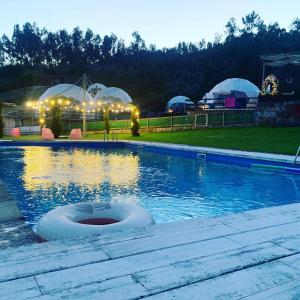 una piscina por la noche con sombrillas de fondo en Guimaglamp, en Guimarães