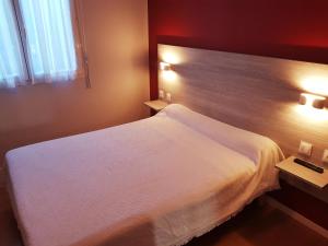 Habitación de hotel con 1 cama blanca y 2 mesas en Hotel Restaurant Le Bourgneuf, en Morlaas