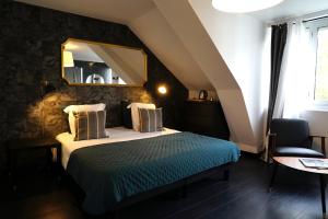 een slaapkamer met een bed met een spiegel en een stoel bij La Villa des Sables in Concarneau