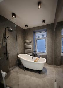 een badkamer met een bad en een glazen douche bij Flat in neo country style aus Gründerzeit bis 6 Person in Leipzig
