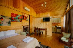 a bedroom with a bed and a table and a kitchen at River Land Cottages in Tsʼkhmorisi