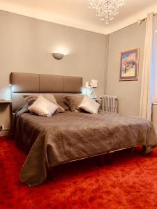 een slaapkamer met een groot bed en een kroonluchter bij Hôtel Le Pré Catelan in Juan-les-Pins