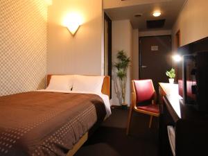 a hotel room with a bed and a chair at HOTEL LiVEMAX BUDGET Utsunomiya in Utsunomiya