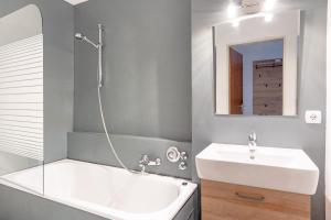 een badkamer met een wastafel, een bad en een spiegel bij Alpenblume in Fischen