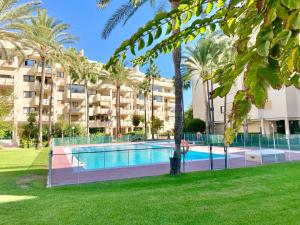 a swimming pool in front of a building with palm trees at SOLANA Montemar Puerto in Torremolinos