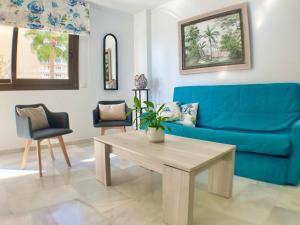 a living room with a blue couch and a table at SOLANA Montemar Puerto in Torremolinos