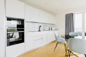 een keuken met witte kasten en een tafel en stoelen bij Executive Waterfront Split Penthouse in Woolwich