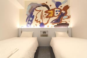 two beds in a room with a painting on the wall at KOKO HOTEL Osaka Namba Ebisucho in Osaka