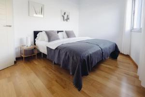 a bed in a white room with a wooden floor at Cornisa Apartments in Patalavaca