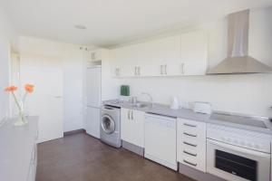 a white kitchen with a sink and a washing machine at Cornisa Apartments in Patalavaca