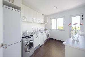 a white kitchen with a washer and dryer in it at Cornisa Apartments in Patalavaca